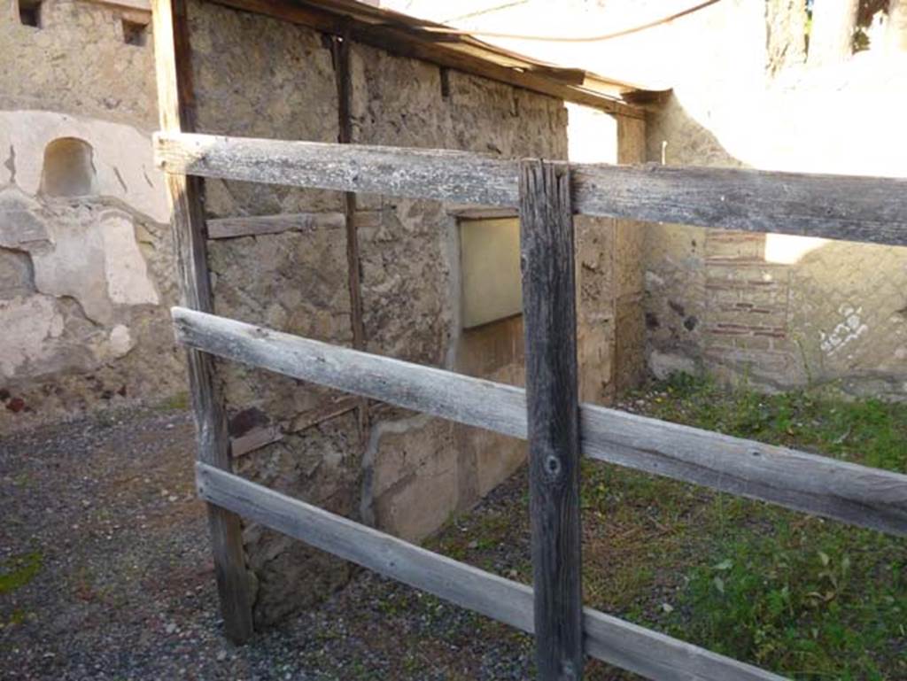 IV.15/16, Herculaneum, October 2012. Looking north-west towards room 6, used by the customers (behind the wooden fence). On the left is the west wall of room 7. Photo courtesy of Michael Binns.